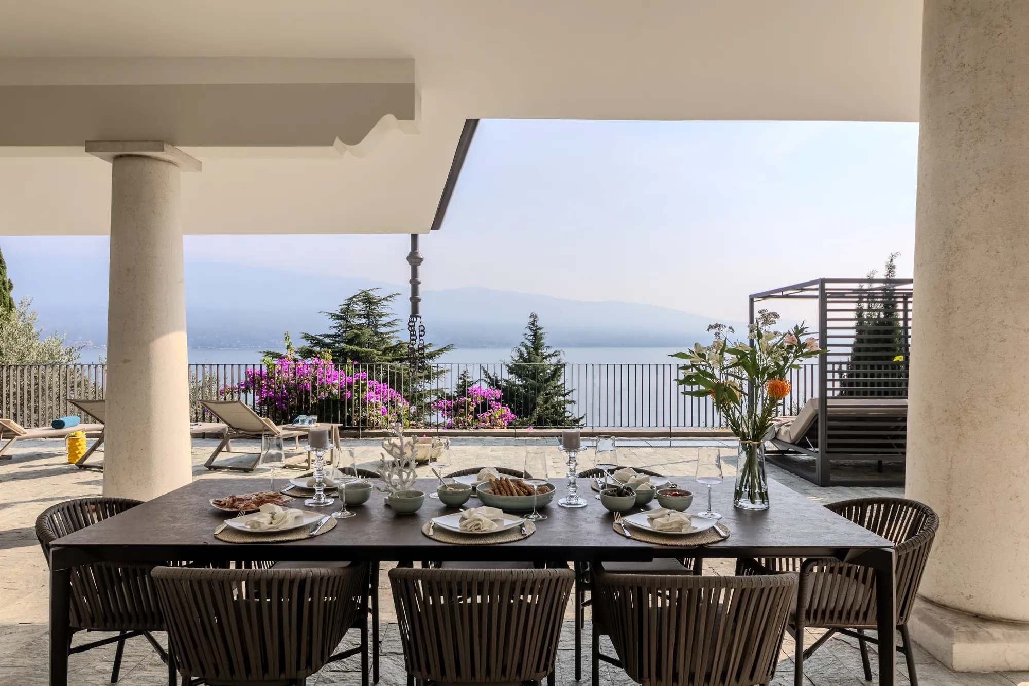 Covered terrace with a table set for lunch, overlooking Lake Garda