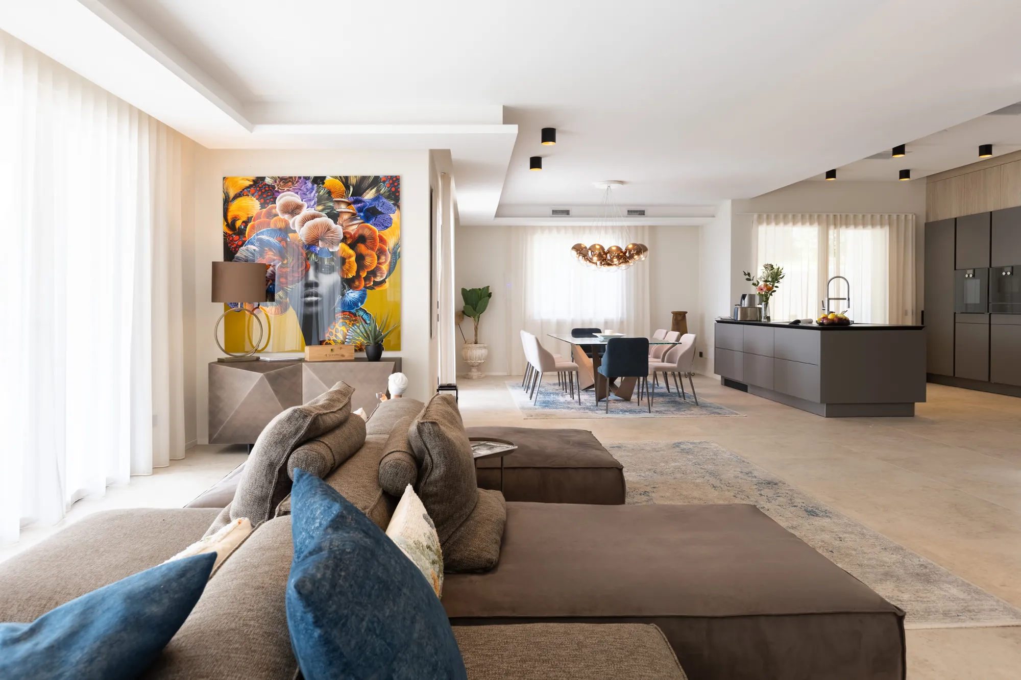 Open-plan living room at Villa Giulia in Gargnano with sectional sofa, contemporary art and the dining area beyond